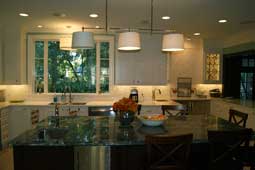 A kitchen with an island finished with a green granite countertop; alternate view